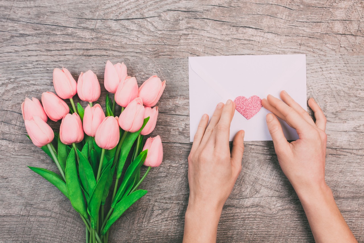 bouquet-pink-tulips-women-s-hands-are-holding-blank-envelope-with-heart-wooden-background
